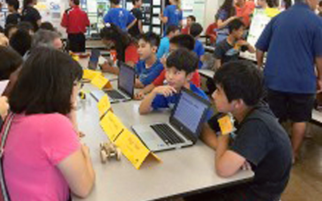 students using laptop to share information with adults in cafeteria