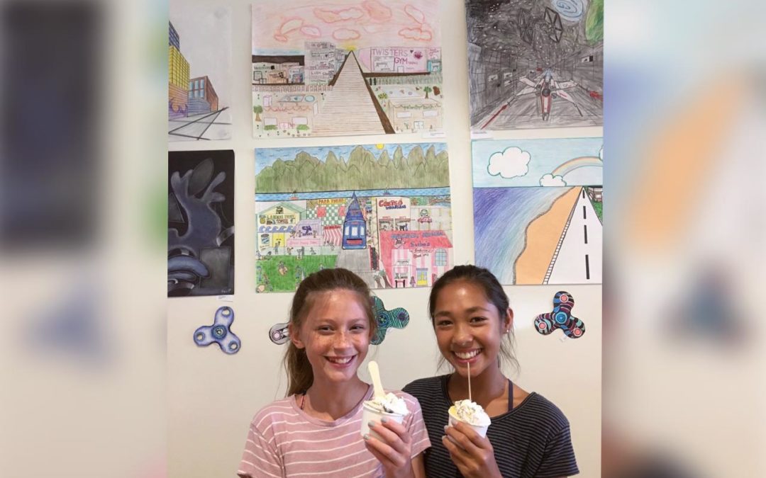 Two girls holding a gelato standing in front of an art exhibit