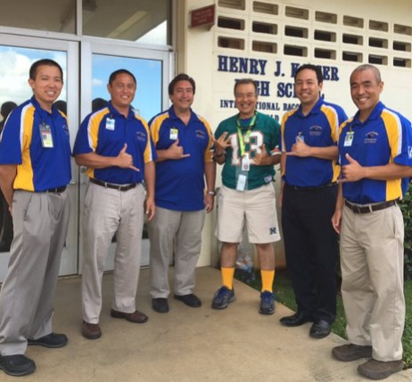 Five men in blue and yellow shirts and one man in football jersey