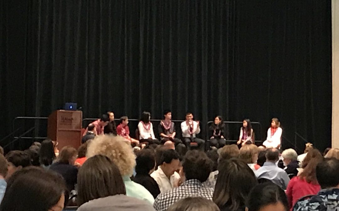 Nine person student panel on stage with audience in the foreground