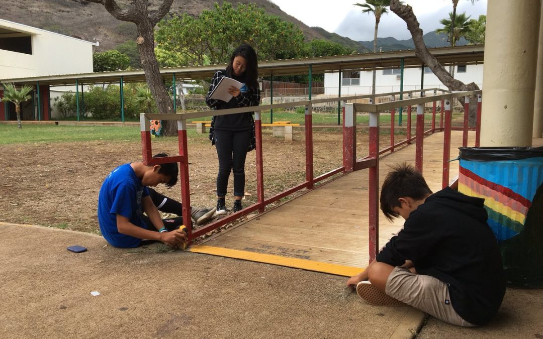 Three students take measurements of the handicap ramp