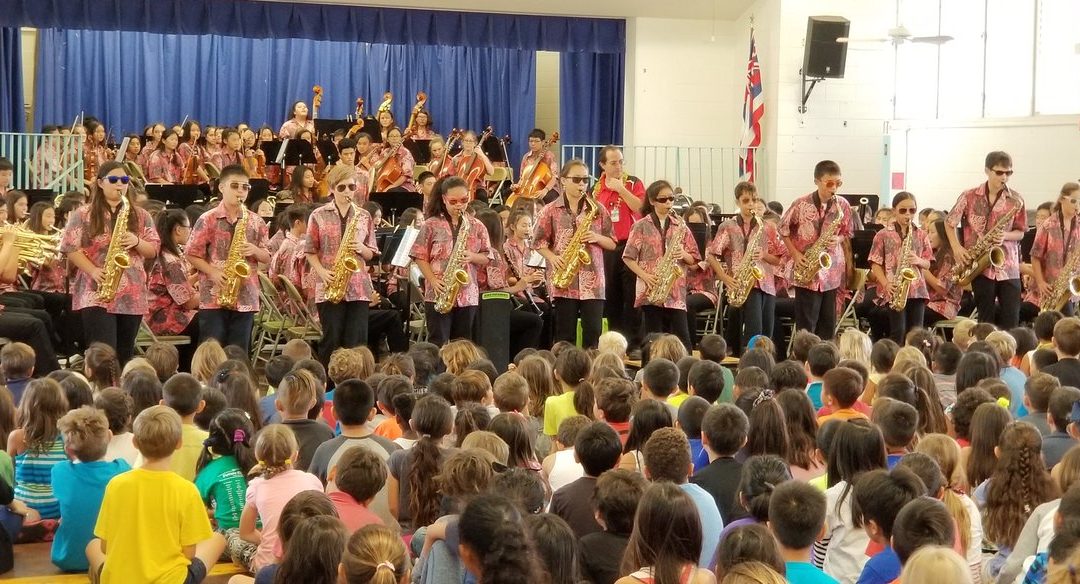 Music students wearing dark glasses play saxophones and perform for younger students