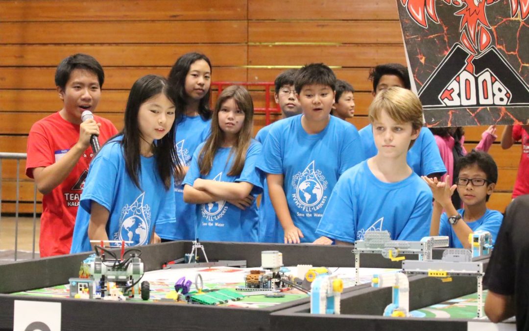 Students in blue shirt control robot on table top