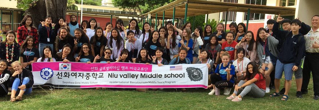 Students from Niu Valley and Seonhwa Middle Schools with pink and white banner