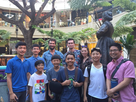 Adults and four students in the courtyard at the Royal Hawaiian Shopping Center