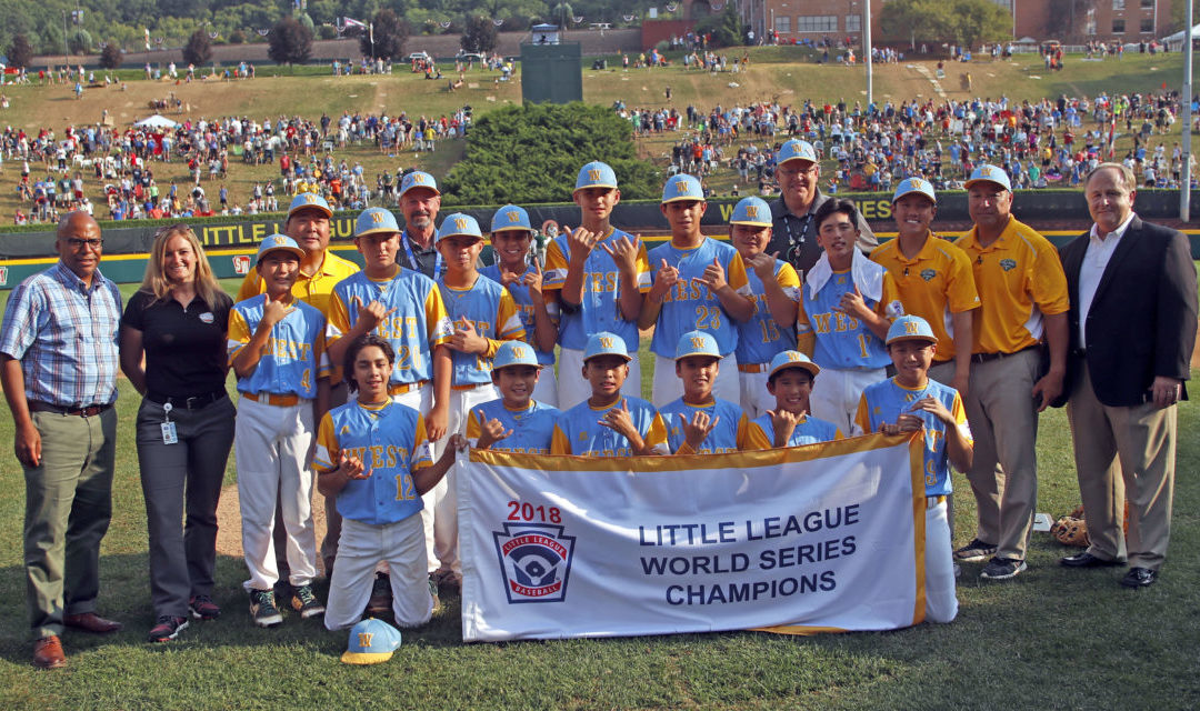 Little League World Series team hold Championship banner with coaches and officials, crowd in background