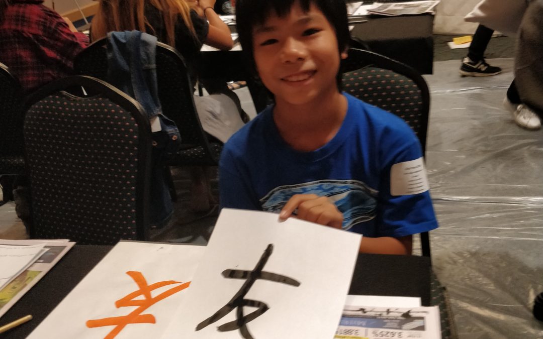 Boy in blue shirt show Japanese calligraphy artwork