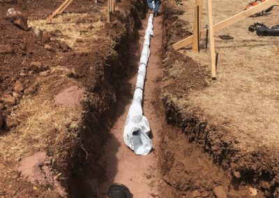 Trenching for Conduit with 2 construction workers standing in trench