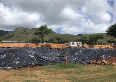 Mounds of dirt covered by grey plastic sheeting at worksite