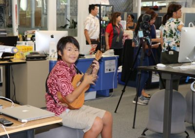 Student sitting on a chair playing an ukulele