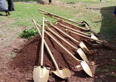Ten gold color shovels resting on a pile of dirt