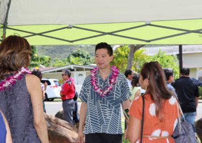Rep. Stanley Chang wearing lei talks to two people at Groundbreaking