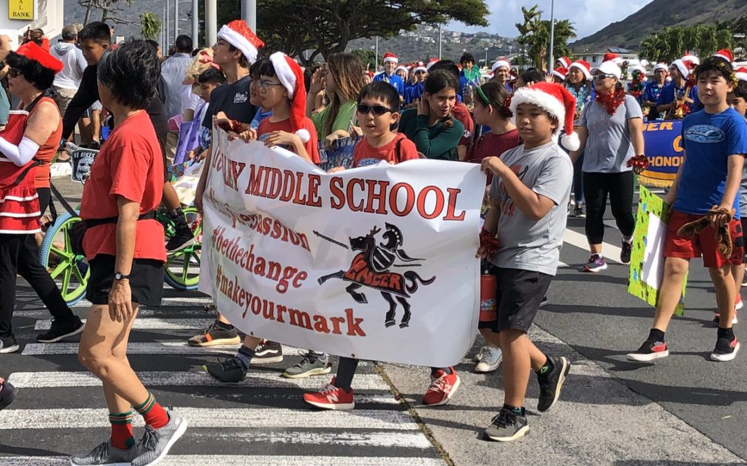 Students wearing Santa hats carrying Niu Valley Middle School banner in the Hawaii Kai Holiday Parade 2019