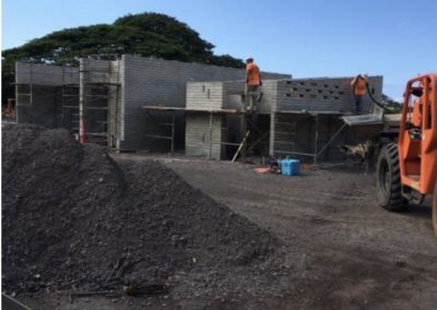 Ongoing completion of concrete walls for restrooms, gravel pile in the foreground