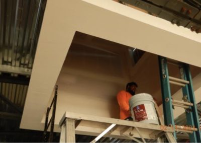 Construction worker standing on scaffold to apply drywall compound on ceiling